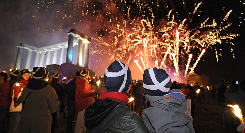 Large crowd by the National Monument of Scotland on bonfire night with fireworks exploding 