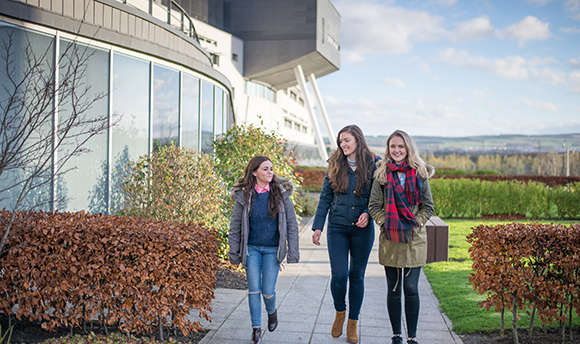 3 girls in winter jackets outside the Queen Margaret University Campus, Edinburgh